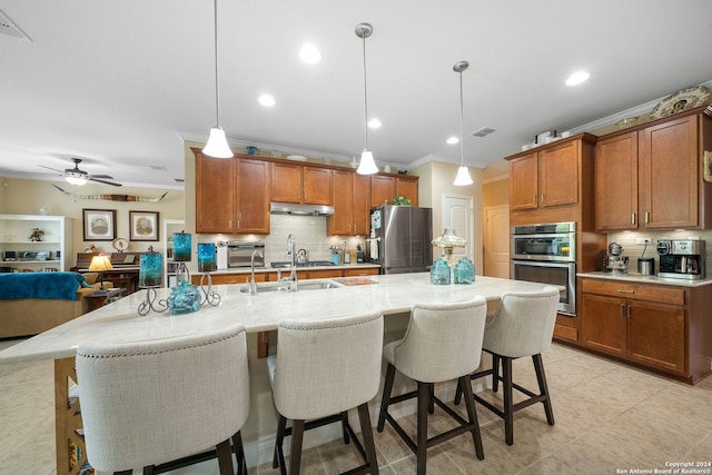 kitchen featuring appliances with stainless steel finishes, hanging light fixtures, a kitchen bar, and a center island with sink