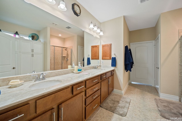 bathroom with a shower with door, vanity, and tile patterned floors