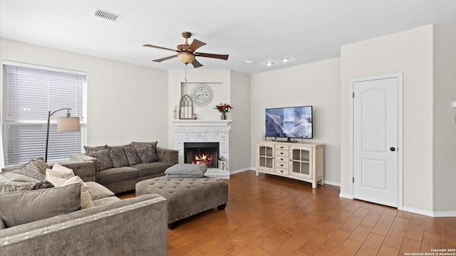 living room with a brick fireplace, ceiling fan, and dark hardwood / wood-style flooring