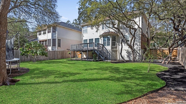 view of yard with a trampoline and a wooden deck