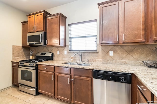 kitchen featuring stainless steel appliances, sink, light tile patterned floors, backsplash, and light stone countertops