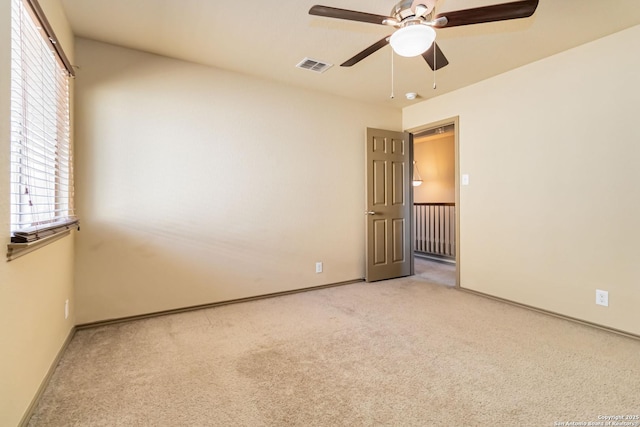 empty room with light carpet, ceiling fan, and plenty of natural light