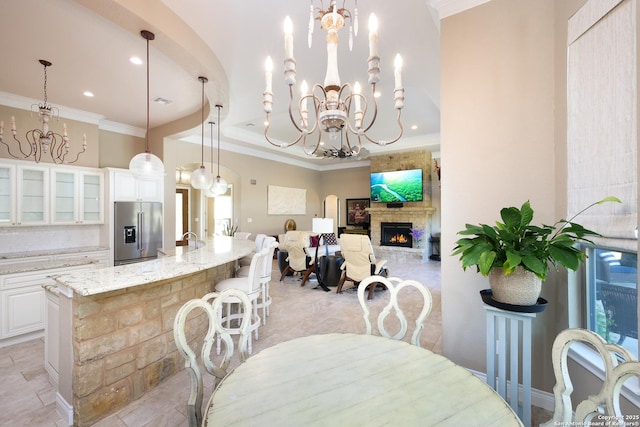 dining room with ornamental molding, a chandelier, and a fireplace