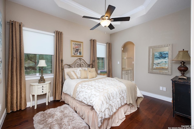 bedroom featuring ceiling fan, dark hardwood / wood-style flooring, connected bathroom, and a raised ceiling