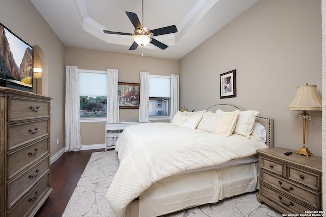 bedroom with a raised ceiling, ceiling fan, ornamental molding, and dark hardwood / wood-style floors