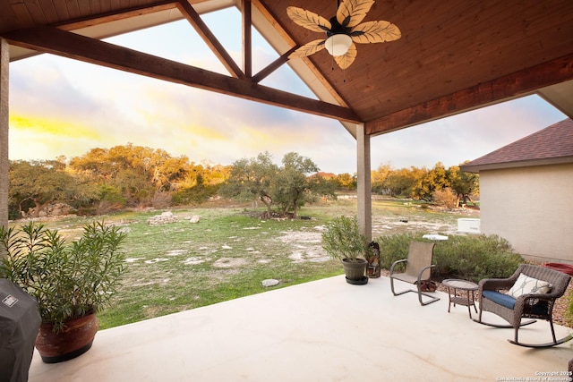 patio terrace at dusk with ceiling fan and a yard