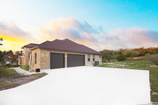 property exterior at dusk with central air condition unit and a garage