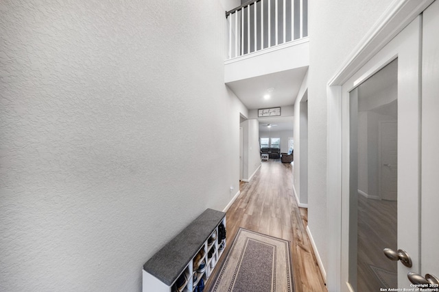 corridor with light hardwood / wood-style flooring and a towering ceiling