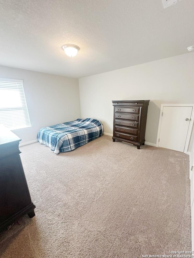 bedroom with light colored carpet and a textured ceiling