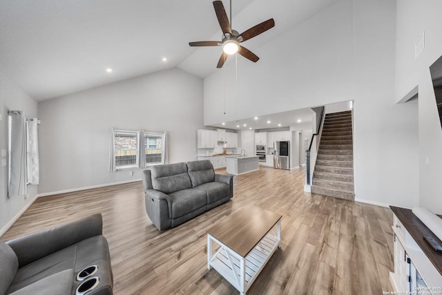 living room with sink, ceiling fan, light hardwood / wood-style flooring, and high vaulted ceiling