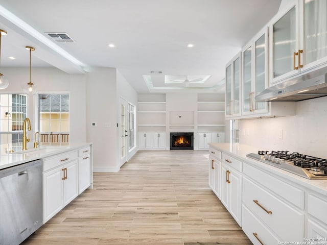 kitchen with sink, white cabinetry, hanging light fixtures, extractor fan, and appliances with stainless steel finishes