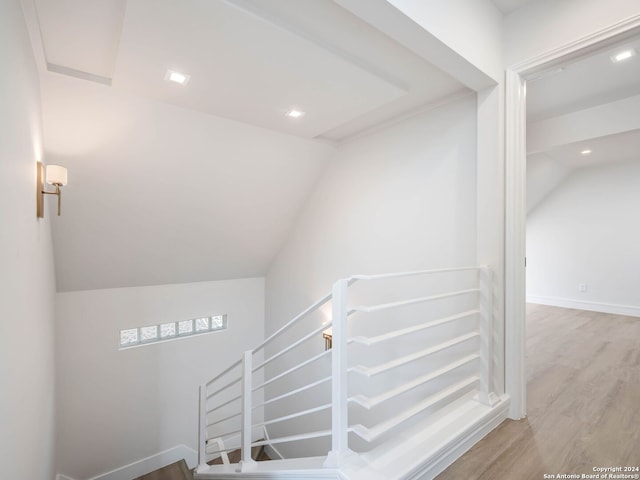 stairway featuring vaulted ceiling and wood-type flooring