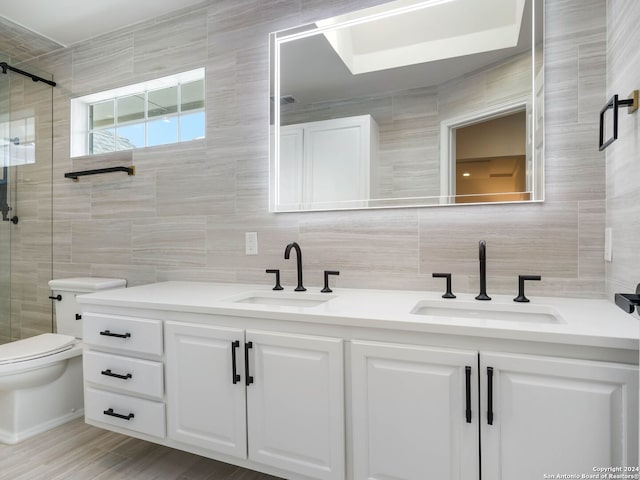 bathroom with toilet, walk in shower, vanity, tile walls, and tasteful backsplash