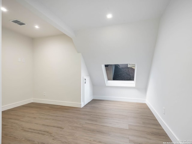 bonus room featuring light wood-type flooring and beam ceiling