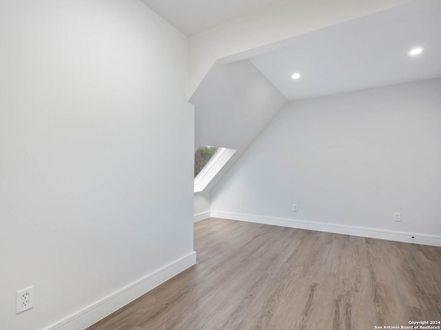 bonus room featuring light wood-type flooring and vaulted ceiling with skylight