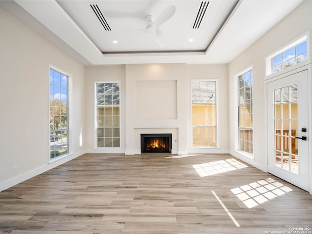 unfurnished sunroom featuring a raised ceiling, ceiling fan, and a healthy amount of sunlight