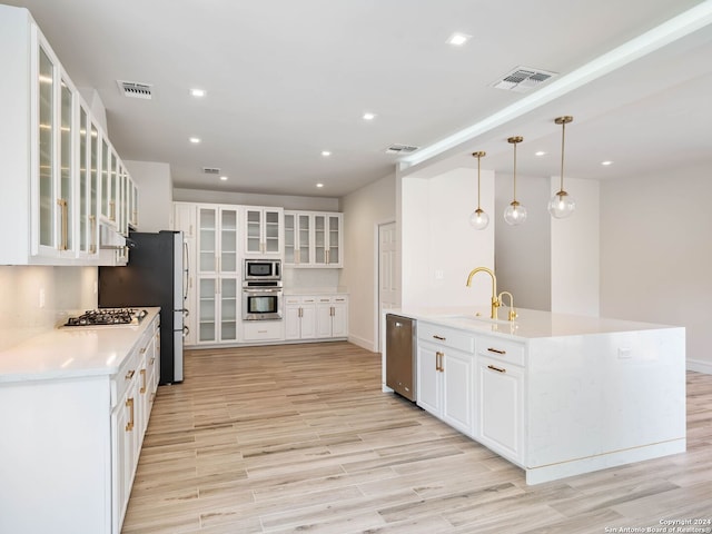 kitchen featuring light hardwood / wood-style flooring, hanging light fixtures, white cabinetry, appliances with stainless steel finishes, and sink