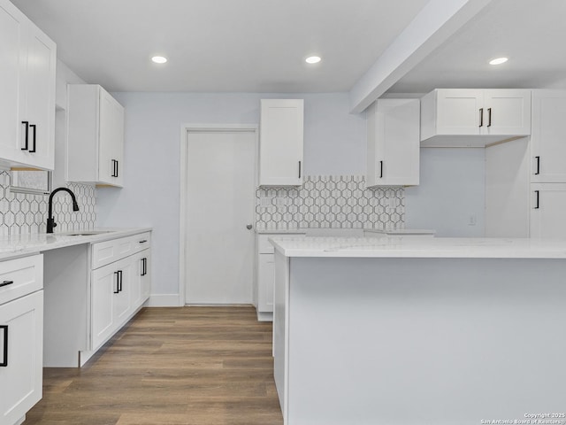 kitchen featuring light stone counters, white cabinets, backsplash, and sink