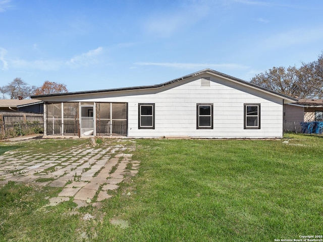 back of house featuring a lawn and a sunroom