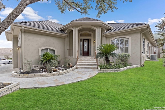 mediterranean / spanish home featuring central air condition unit and a front lawn