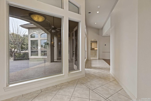 entryway with ceiling fan, light tile patterned floors, and crown molding