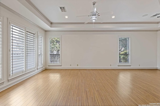 empty room with light hardwood / wood-style floors, ceiling fan, and a tray ceiling