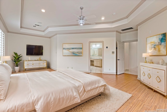 bedroom featuring crown molding, ensuite bath, and a tray ceiling