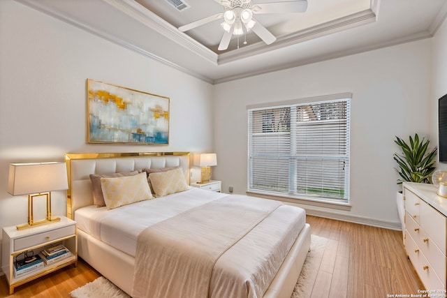 bedroom featuring a raised ceiling, ceiling fan, crown molding, and light wood-type flooring