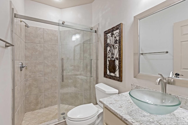 bathroom with toilet, vanity, and a shower with shower door