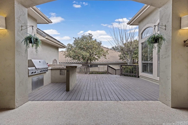 wooden deck with exterior kitchen and a grill