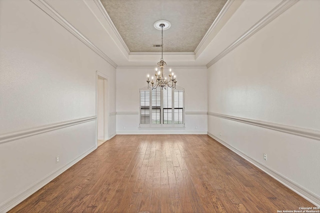 unfurnished dining area featuring a notable chandelier, crown molding, hardwood / wood-style floors, and a raised ceiling