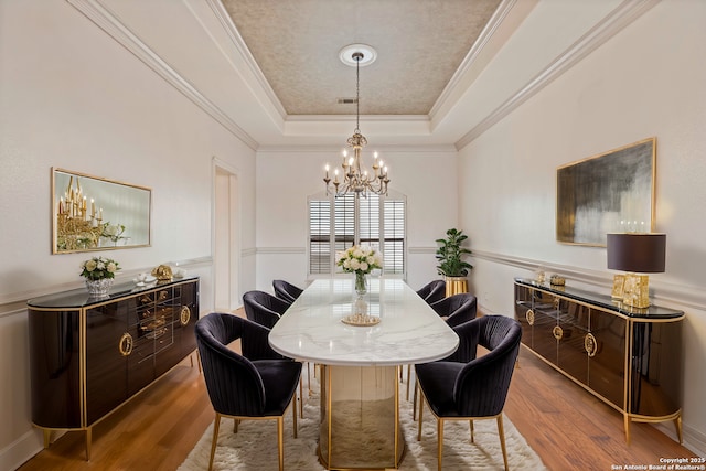 dining space featuring a chandelier, crown molding, hardwood / wood-style flooring, and a tray ceiling