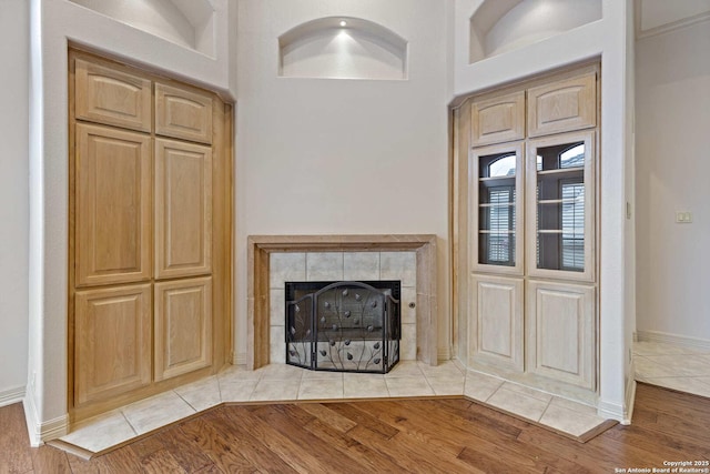 unfurnished living room with a tiled fireplace and light hardwood / wood-style flooring