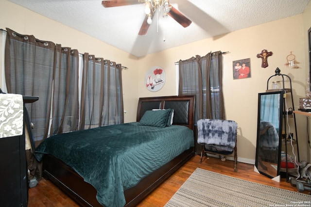 bedroom with ceiling fan, hardwood / wood-style floors, and a textured ceiling