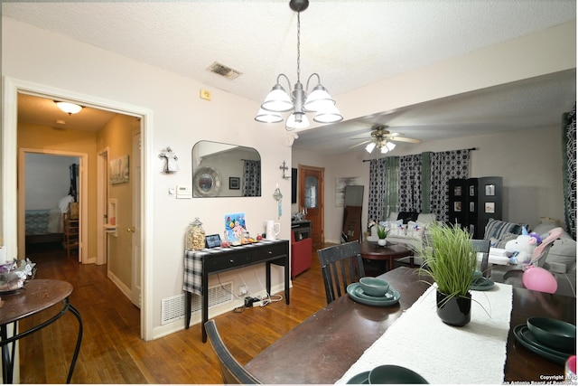 dining room with ceiling fan with notable chandelier, a textured ceiling, and dark hardwood / wood-style floors