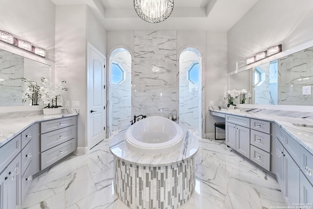 bathroom featuring vanity, an inviting chandelier, and tiled bath