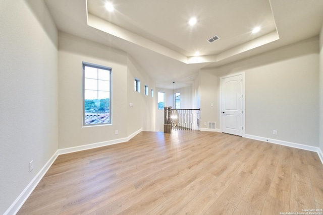 unfurnished living room with a tray ceiling and light hardwood / wood-style flooring