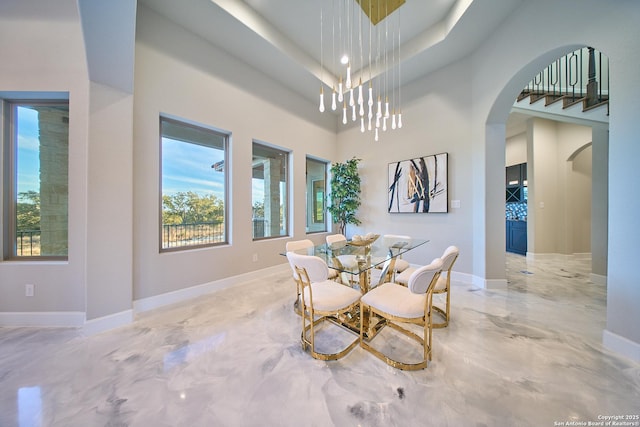 dining area featuring a towering ceiling, a chandelier, and a tray ceiling