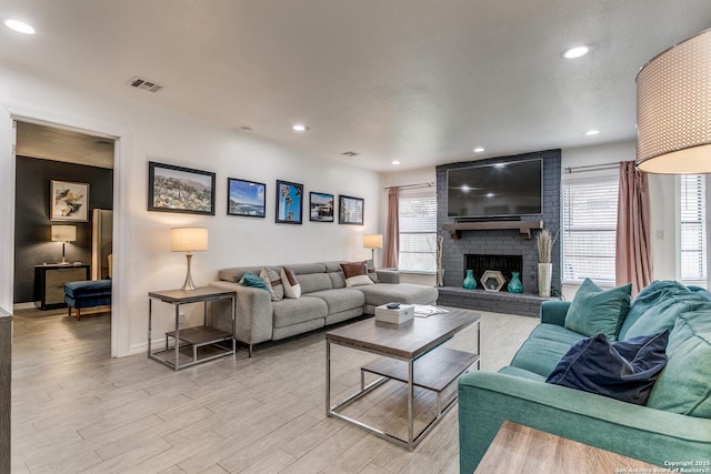 living room with a fireplace, light hardwood / wood-style floors, and plenty of natural light