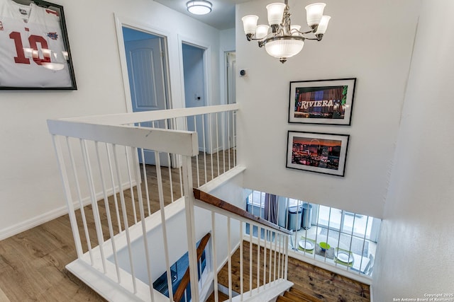 stairway featuring hardwood / wood-style flooring and an inviting chandelier