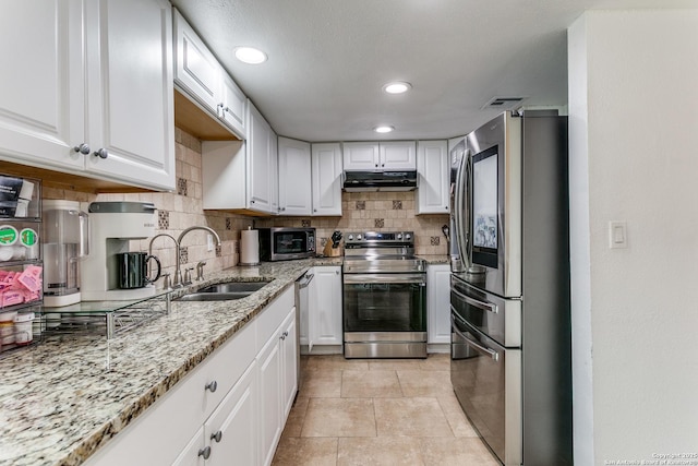 kitchen with sink, white cabinetry, light stone countertops, and appliances with stainless steel finishes