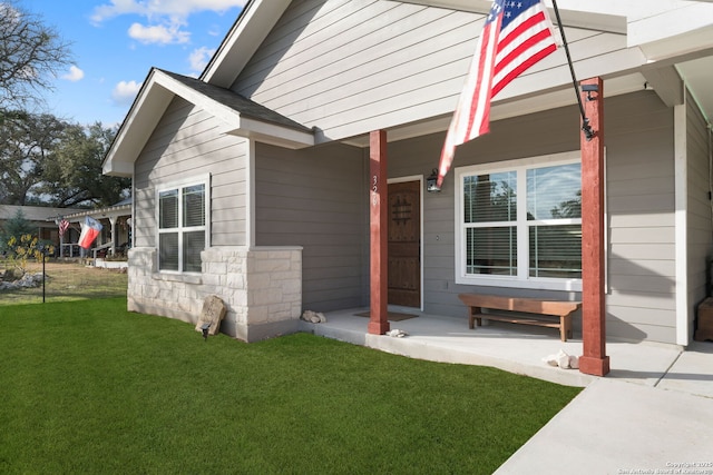 doorway to property with covered porch and a lawn