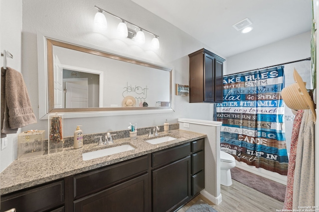 bathroom with a shower with curtain, toilet, vanity, and wood-type flooring