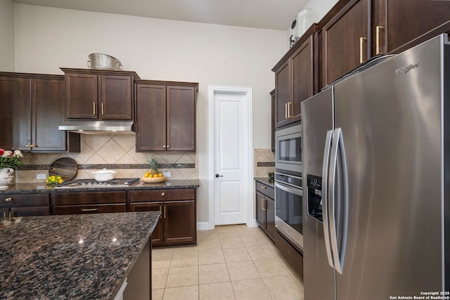 kitchen featuring stainless steel appliances, light tile patterned flooring, dark brown cabinets, and dark stone counters