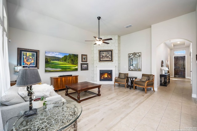 living room featuring a large fireplace, ceiling fan, and light hardwood / wood-style flooring