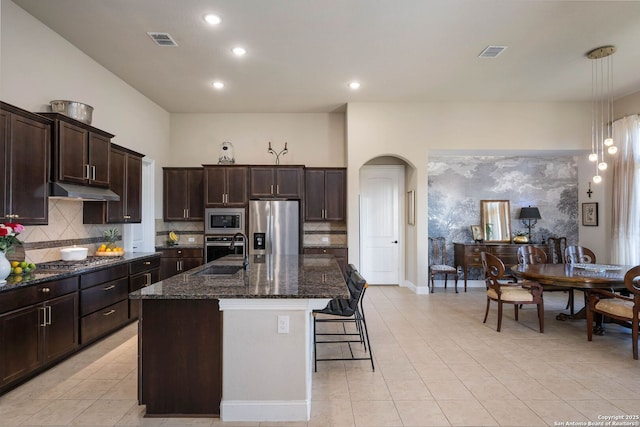 kitchen with sink, decorative light fixtures, light tile patterned flooring, an island with sink, and appliances with stainless steel finishes