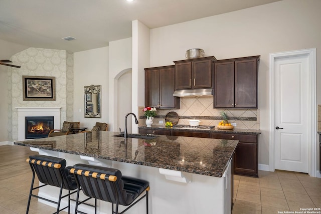 kitchen with a breakfast bar, dark brown cabinets, and sink