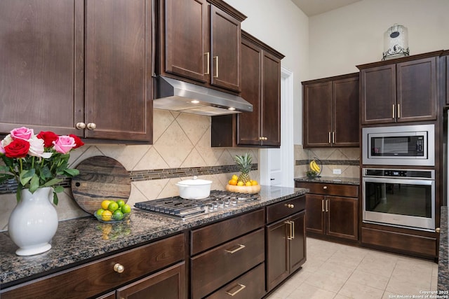 kitchen with decorative backsplash, dark brown cabinetry, dark stone counters, and appliances with stainless steel finishes