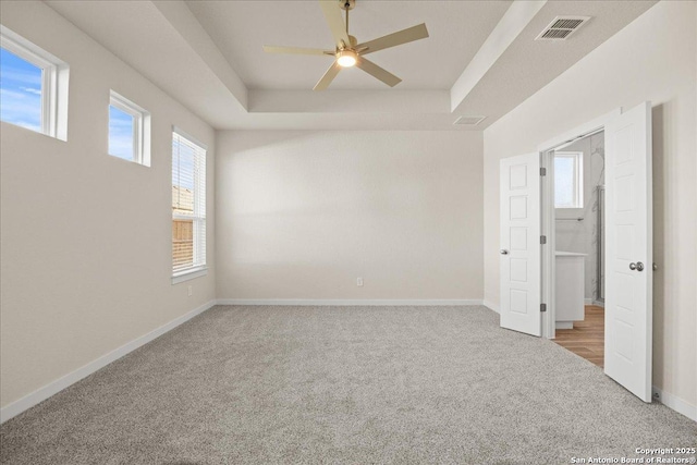 carpeted spare room with ceiling fan and a tray ceiling