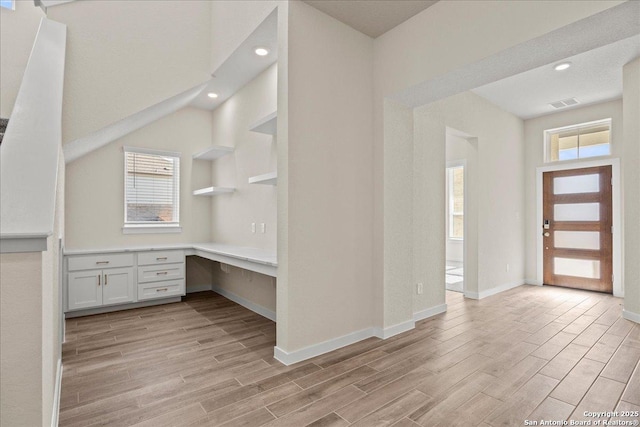 kitchen with built in desk, light wood-type flooring, white cabinets, and plenty of natural light